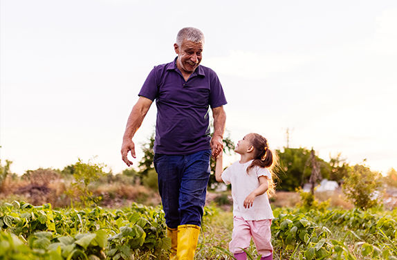 Older man and child walking outdoors smiling holding hands