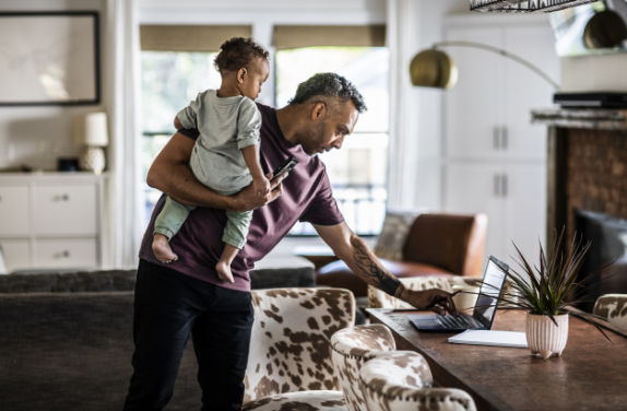 Man holding baby looking at laptop